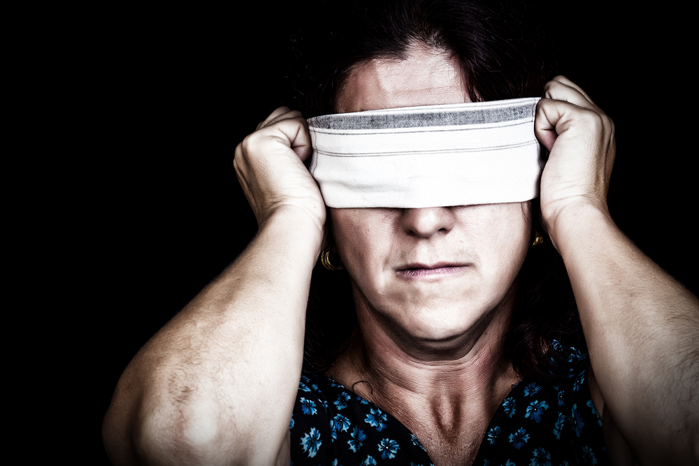 image of a serious woman with a handkerchief covering her eyes to avoid seeing isolated on black