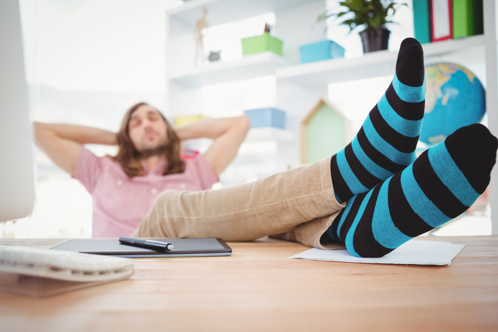 Hipster resting with legs on desk in office